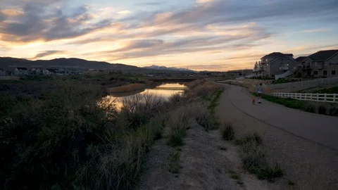 Man skateboards down a path with his dog during a beautiful sunset Stock Footage 106737957