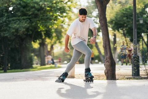 Man skating with inline skates in a paved path of a park Stock Photos