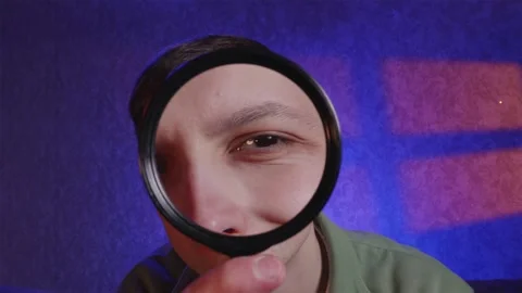 Man skeptically examining camera lens through magnifying glass Stock Footage 333757037