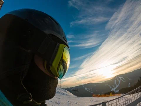 Man in ski mask close up. reflection. snowed mountains on sunset Stock Photos