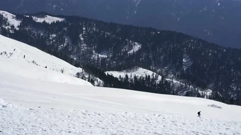 Man skier with backpack skiing in distance in snowy mountains winter sport Stock Footage 195506324