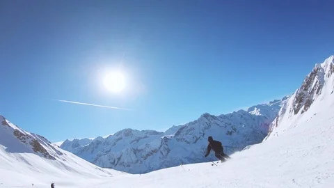 Man skiing down the slope in Ponte di Legno. There is a beautiful blue sky. Stock Footage 124253498