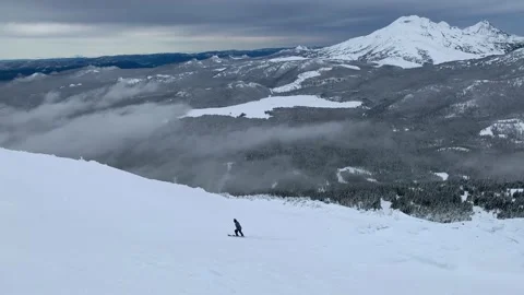 A man skiing down a steep mountain slope surrounded by beautiful breathtaking Stock Footage 220240734