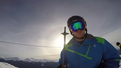 Man skiing taking selfie with selfie stick on top of mountain and chair lift Stock Footage 61863386