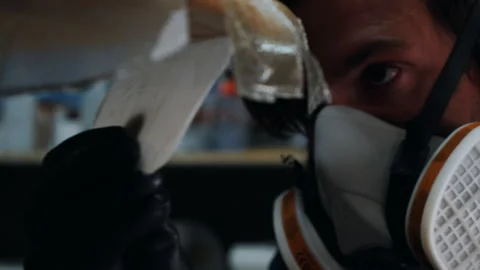 Man skillfully paints unique mask on surfboard in creative workshop Stock Footage 321585659