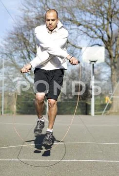 Man skipping fancily with a jump rope outdoors Stock Photos