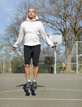 Man skipping outdoors on a basketball court Stock Photos