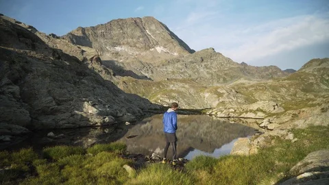 Man skipping stone on a small lake in mountain landscape, 4K Stock Footage 129614465