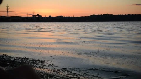 Man skipping stones in lake or river in dusk Stock Footage