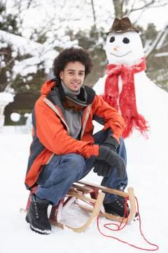 Man with sledge next to snowman Stock Photos