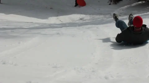 Man Sleds Down Snow Covered Slope and into House Stock Footage 35438326