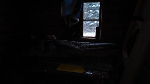 Man in Sleeping Bag Waking Up and Looking Out Window in Winter Cabin Video stock 334239169