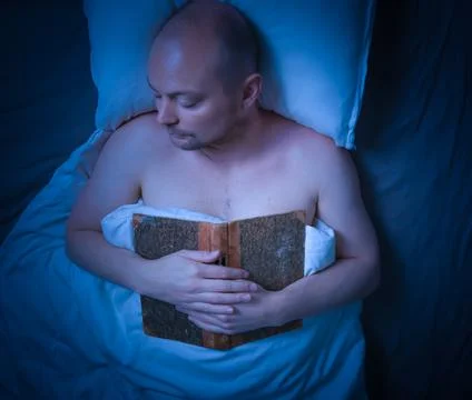 Man sleeping in bed after reading a book. 스톡 사진