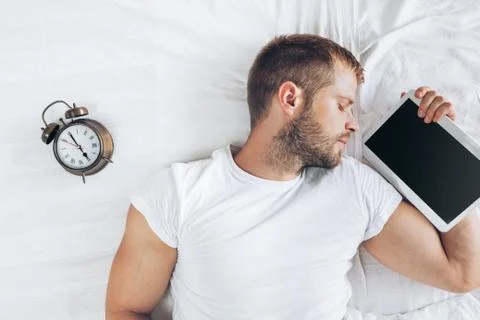Man sleeping on bed after using his digital tablet Stock Photos