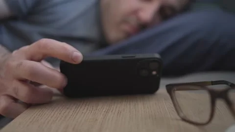 Man Sleeping in Bed Being Wake Up By a Smartphone Notification on His Nightst Stock Footage 169048347
