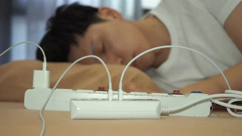 Man sleeping on the bed with electronic wire; phone charging on the bed Stock Footage 129536001