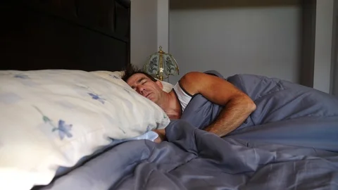 Man sleeping in bed in morning with morning sun, 4k, 60fps. Stock Footage 116335953
