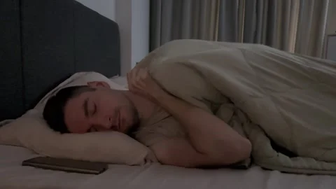 Man sleeping in bed with smartphone on pillow Stock Footage 283404187