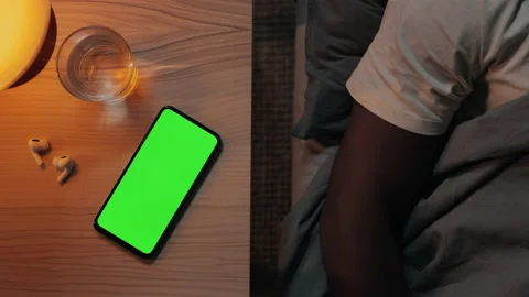 Man sleeping in bed while green screen mobile lying on table Stock Footage 162840400