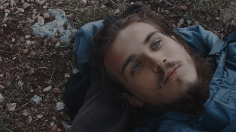 Man sleeping on the floor waking up in dawn on a cliff above the ocean Stock Footage 121805960