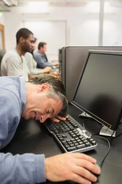 Man sleeping at the keyboard in computer class Stock Photos