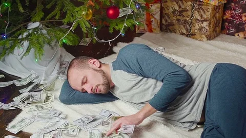 A man is sleeping with a lot of dollars and a Christmas tree Vídeo Stock 81550125