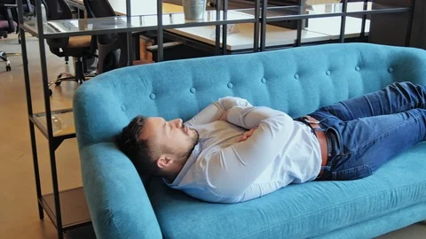 Man sleeping in the office lounge Stock Footage 94703554