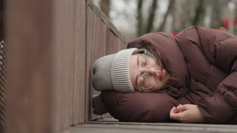 Man sleeping peacefully on wooden deck closeup, knit hat and round glasses Stock Footage 345553348