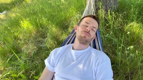 A man sleeping swinging in a hammock outdoors Stock Footage 312815595