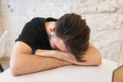 A man is sleeping at a table in a cafe. Stock Photos