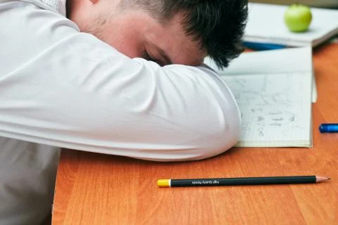 A man sleeping on a table with a notebook and a pencil university, college Stock Photos