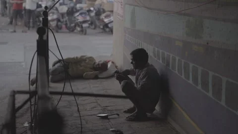 A man sleeping under a bridge and another man begging in Mumbai, India Stockbeeldmateriaal 345388964