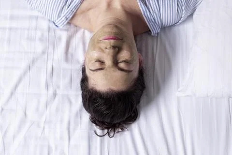Man sleeping on white bed sheets top view Stock Photos