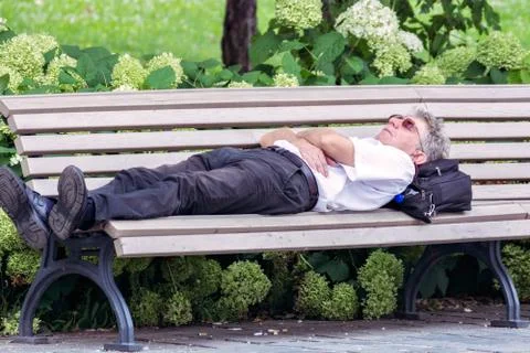 A man sleeps on a bench. Stock Photos