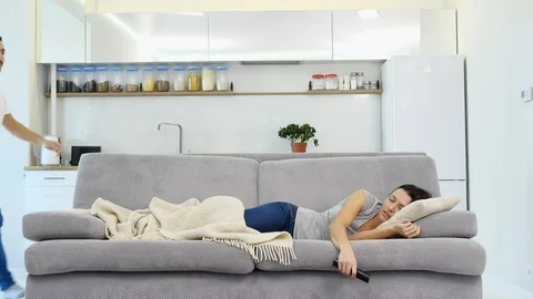 A man sleeps on the floor while his wife watches a TV on the couch  Video stock 99846128