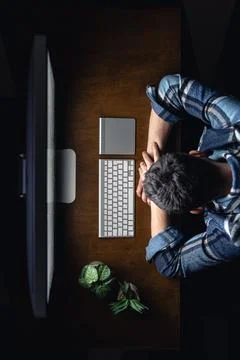 A man sleeps, lying in front of a computer on his desktop at night, top view. Foto stock