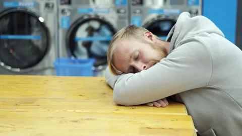A man sleeps in a public laundry while waiting for laundry Video stock 272164745