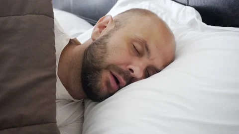 A man sleeps on a snow-white bed. Sweet morning dream. Vídeo Stock 133444556