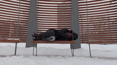 A man sleeps on a swing in winter. Video stock 145967899