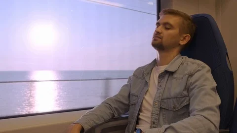 A man sleeps with the train near the window. A man sits in the train and leaning Stock Footage 118967127