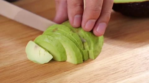 Man slice peeled avocado on cutting board. Cutting an avocado in pieces. Stock Footage 139731196