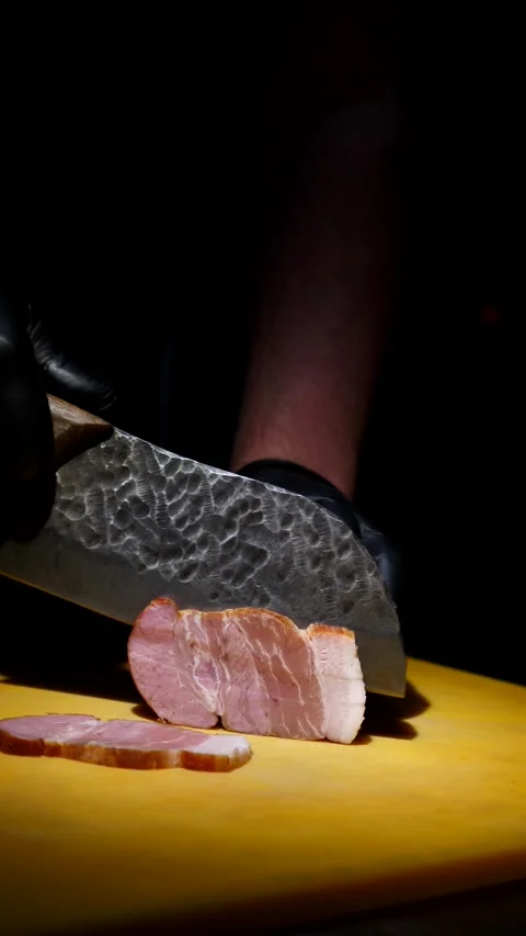Man slices ham bacon meat into thin pieces on cutting board. Chef prepares Stock Footage 309276215