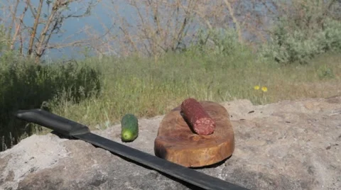 Man slices salami on the stone using a machete Vídeo Stock 62476713