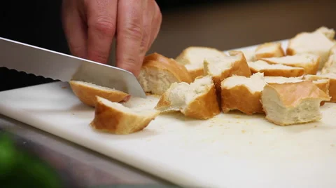  a man slicing bread with a knife in a kitchen on a cutting board. Stock Footage 57400592