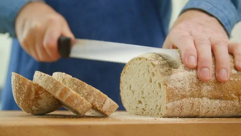 Man Slicing Crusty Bread With Knife In Kitchen Stock Footage 86072206