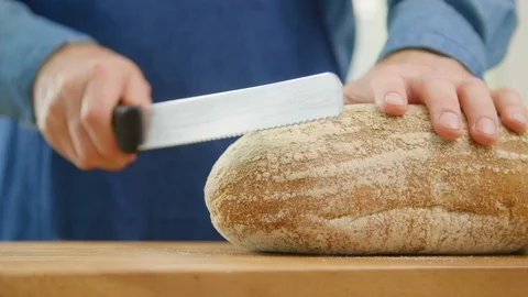 Man Slicing Crusty Loaf Of Bread With Knife On Board Stock Footage 86072179