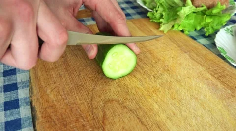 Man Slicing Cucumber on a Kitchen Table Stock Footage 49912751