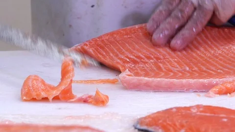 Man slicing a fillet of salmon at table in a fish shop. Close up. Dolly shot. Stock Footage 69835792