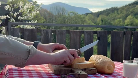 Man slicing fresh bread on rustic terrace outdoors Stock-Footage 333526069