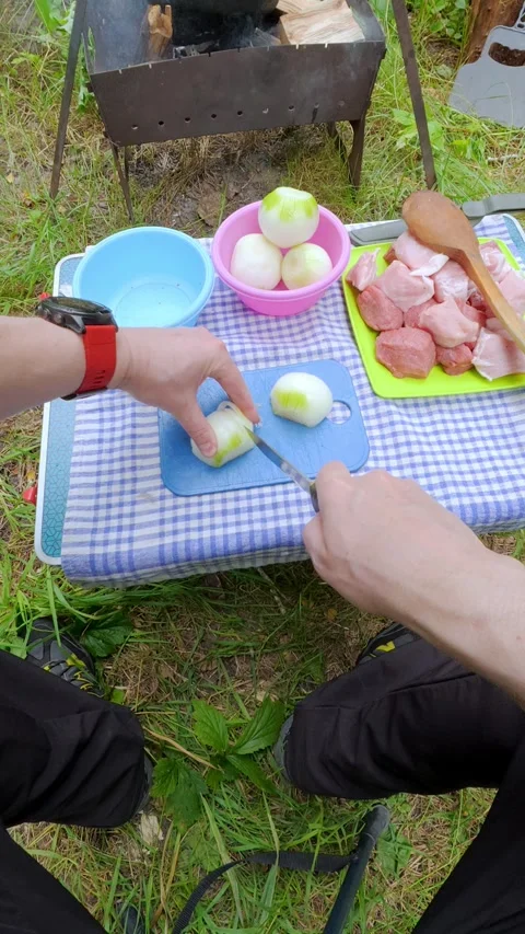 Man slicing fresh onion on table for outdoor camping barbecue picnic food p.. Video stock 344310105